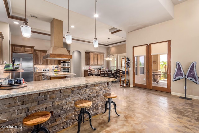 kitchen with light stone counters, hanging light fixtures, a raised ceiling, and built in refrigerator