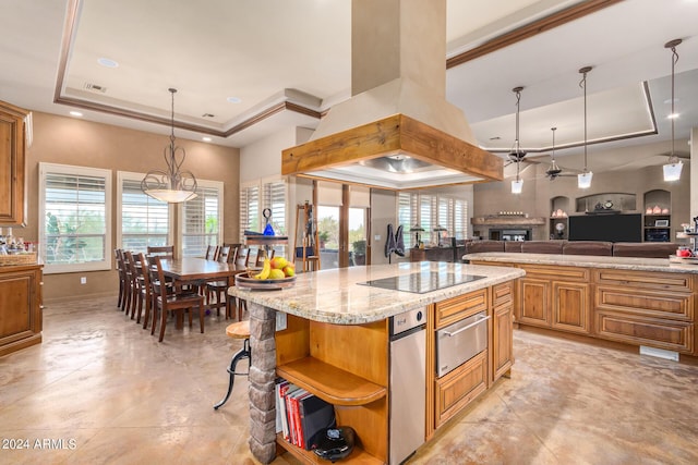 kitchen with a kitchen island, island range hood, black electric stovetop, a tray ceiling, and light stone countertops