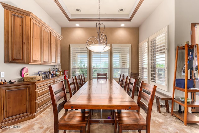 dining area with a raised ceiling, crown molding, and a healthy amount of sunlight