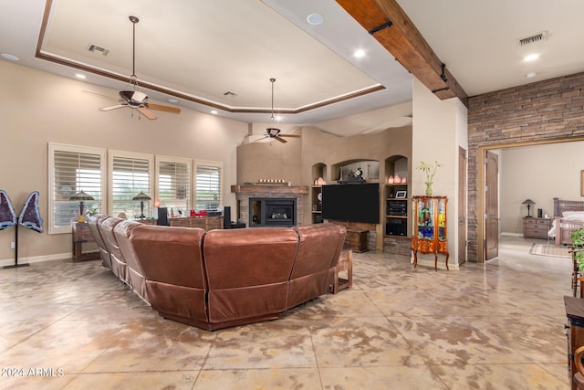 living room with a high ceiling, ceiling fan, and a tray ceiling