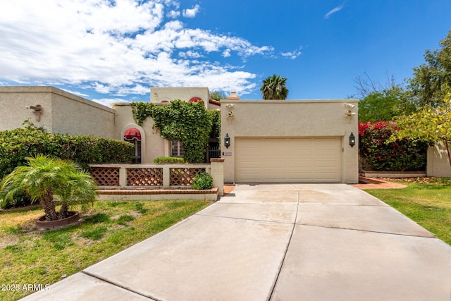 pueblo-style house featuring driveway, stucco siding, and a garage