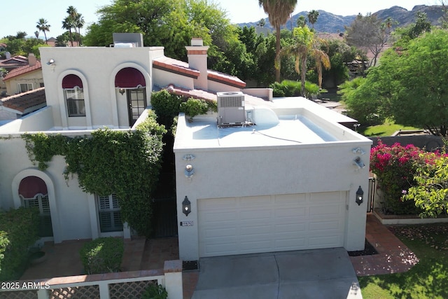 mediterranean / spanish house with stucco siding, central AC, concrete driveway, a mountain view, and a garage