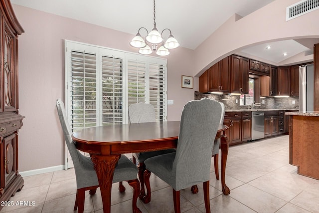 dining space with vaulted ceiling, a chandelier, arched walkways, light tile patterned flooring, and baseboards
