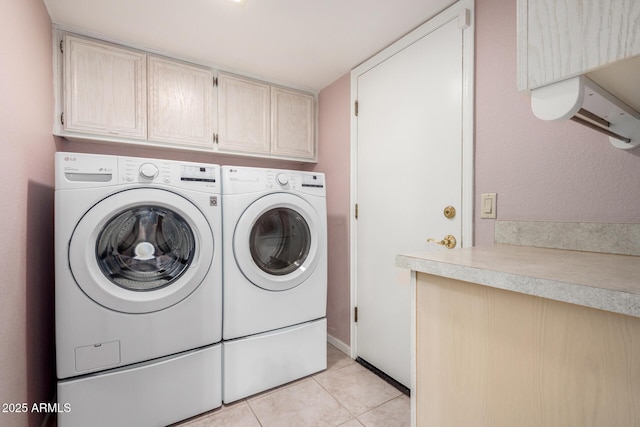 clothes washing area featuring washing machine and clothes dryer, cabinet space, and light tile patterned floors