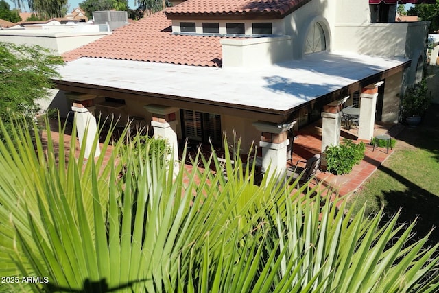 rear view of property with a tiled roof, stucco siding, and a patio area