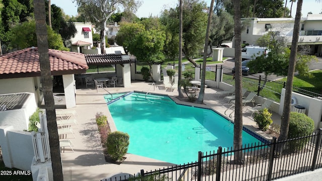 community pool featuring fence, a patio, and a residential view