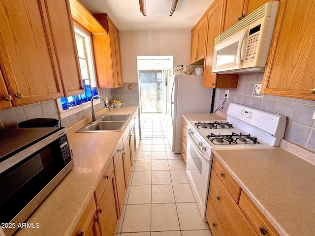 kitchen with white appliances, tasteful backsplash, light tile patterned floors, light countertops, and a sink