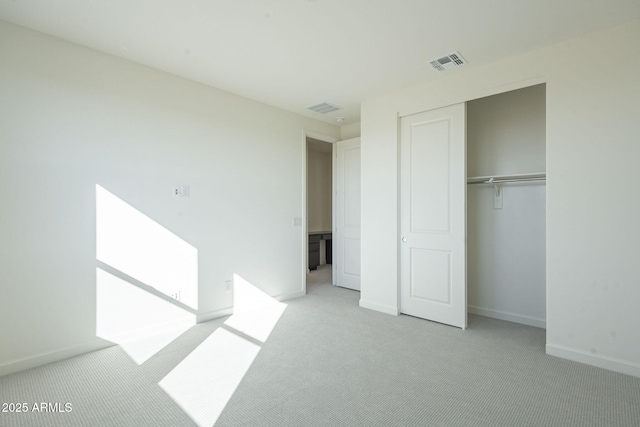 unfurnished bedroom with light colored carpet and a closet