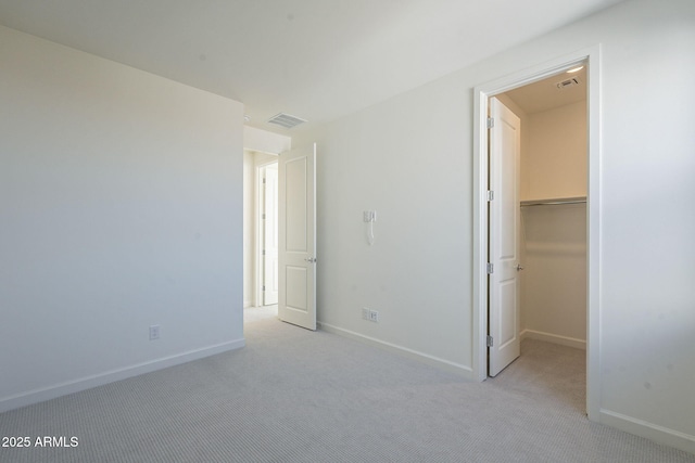 unfurnished bedroom with a walk in closet and light colored carpet