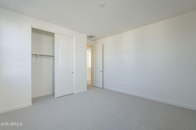 unfurnished bedroom featuring light carpet and a closet