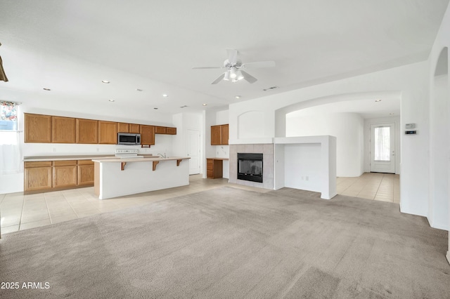 unfurnished living room featuring a fireplace, ceiling fan, and light tile patterned flooring