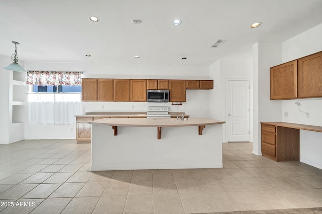 kitchen featuring range, hanging light fixtures, a breakfast bar area, and an island with sink