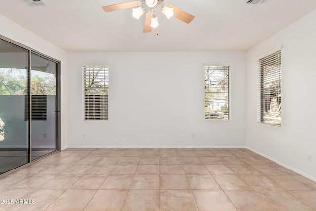 spare room with a ceiling fan, visible vents, and baseboards