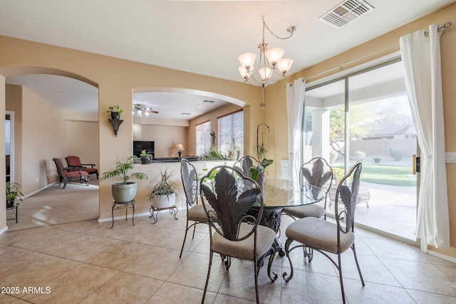 tiled dining space featuring ceiling fan with notable chandelier