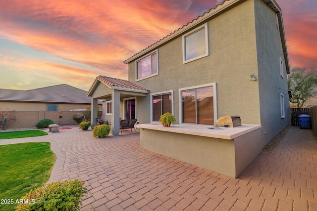 back house at dusk featuring area for grilling and a patio area