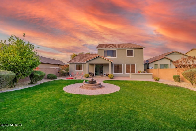 back house at dusk with a fire pit, a patio area, and a lawn