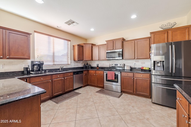 kitchen featuring backsplash, appliances with stainless steel finishes, sink, and dark stone countertops