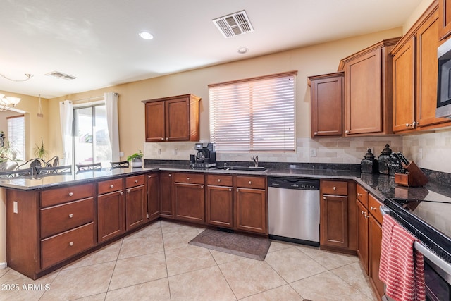 kitchen featuring sink, decorative backsplash, dark stone counters, and appliances with stainless steel finishes