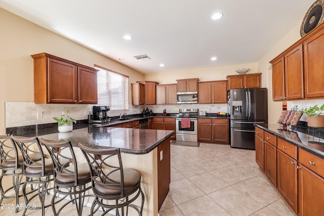 kitchen featuring appliances with stainless steel finishes, a breakfast bar, sink, decorative backsplash, and light tile patterned floors