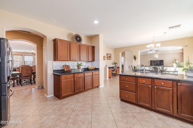 kitchen with tasteful backsplash, light tile patterned floors, stainless steel fridge, and a chandelier