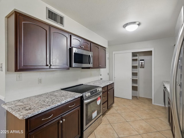 1306 W 12th St, Tempe, AZ 85281 - kitchen featuring stainless steel appliances, dark brown cabinetry, light tile patterned floors, light stone counters, and a textured ceiling