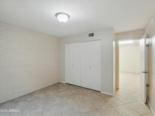 1306 W 12th St, Tempe, AZ 85281 - unfurnished bedroom featuring brick wall, a closet, and light tile patterned floors