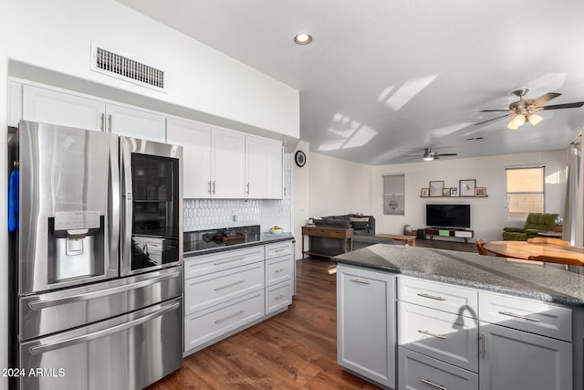 kitchen with stainless steel refrigerator with ice dispenser, dark stone counters, white cabinetry, and dark wood-type flooring