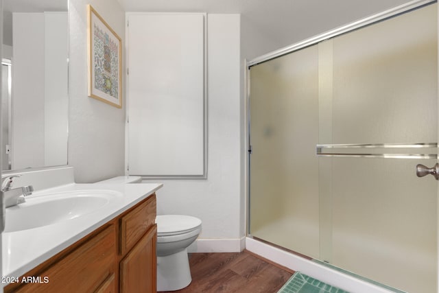 bathroom with hardwood / wood-style floors, vanity, an enclosed shower, and toilet