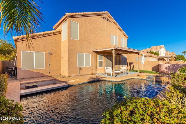 rear view of house featuring a fenced in pool and a patio