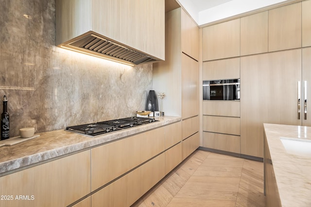 kitchen featuring tasteful backsplash, custom range hood, stainless steel gas cooktop, and light brown cabinets