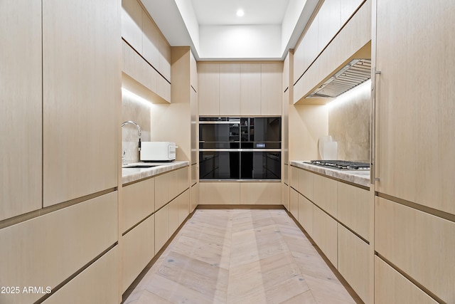 kitchen with black double oven, sink, stainless steel gas cooktop, and light tile patterned floors