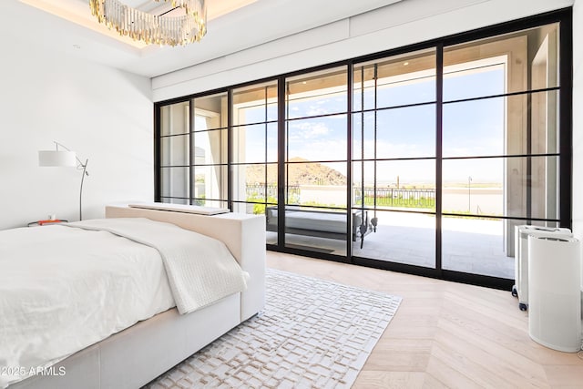 bedroom featuring an inviting chandelier, access to outside, and light parquet floors