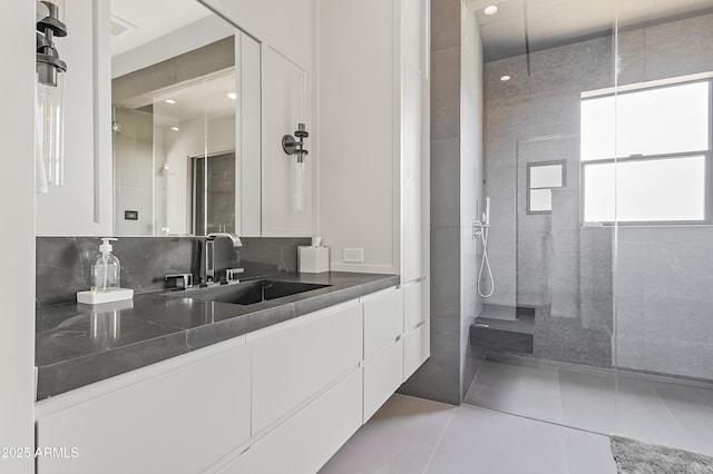 bathroom with tasteful backsplash, vanity, a tile shower, and tile patterned floors