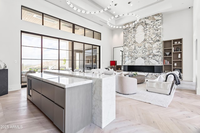 living room featuring a raised ceiling, light parquet floors, and a high ceiling