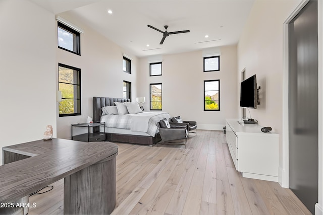 bedroom with multiple windows, a towering ceiling, and light hardwood / wood-style flooring