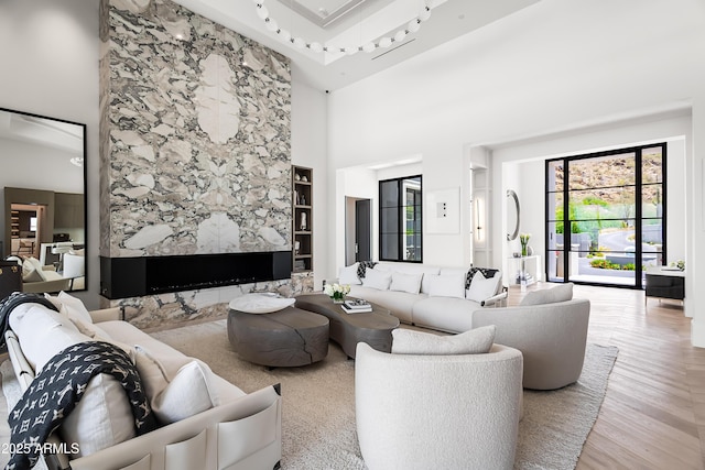 living room featuring a towering ceiling, light hardwood / wood-style floors, and built in shelves