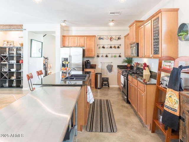 kitchen featuring visible vents, dark countertops, appliances with stainless steel finishes, concrete flooring, and a sink