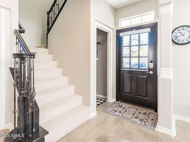 entryway featuring concrete flooring, stairway, and baseboards