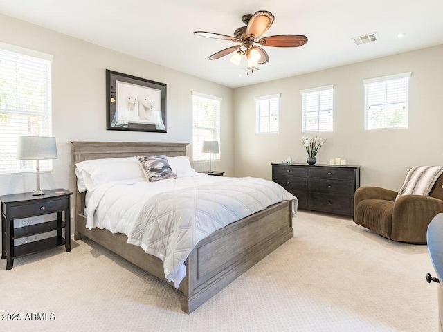 bedroom with ceiling fan, visible vents, and light colored carpet