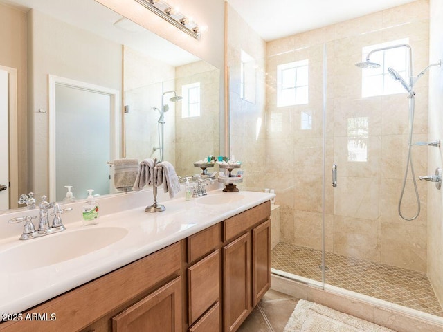 bathroom with double vanity, a stall shower, tile patterned flooring, and a sink