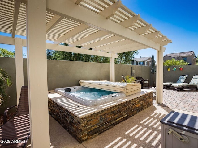 view of patio / terrace featuring an outdoor hot tub, fence, and a pergola