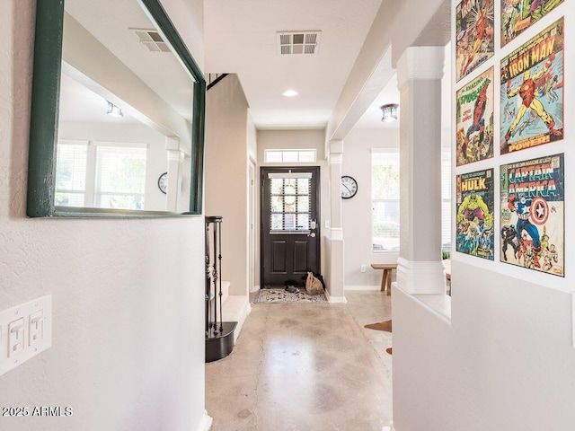 entryway featuring a healthy amount of sunlight, visible vents, concrete floors, and ornate columns