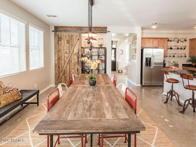 dining area with baseboards, a barn door, visible vents, and finished concrete floors