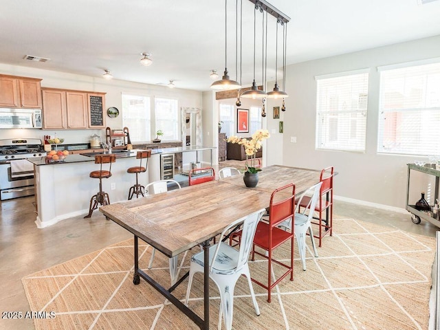 dining area with concrete flooring, beverage cooler, visible vents, and baseboards