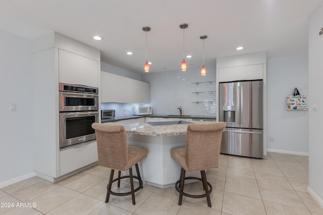 kitchen with decorative backsplash, appliances with stainless steel finishes, pendant lighting, and white cabinetry