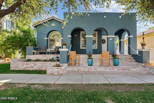 mediterranean / spanish-style home with covered porch, an outdoor living space, and stucco siding