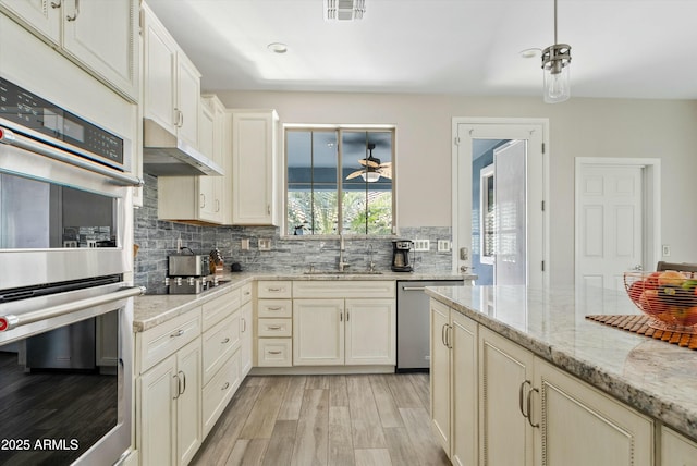 kitchen featuring visible vents, light stone countertops, cream cabinets, stainless steel appliances, and a sink