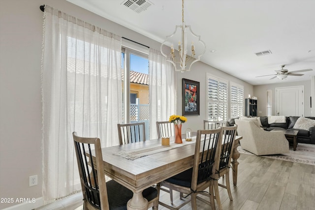 dining space featuring ceiling fan with notable chandelier, light hardwood / wood-style floors, and a healthy amount of sunlight