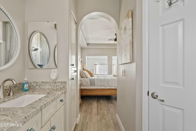 bathroom with wood finished floors, ensuite bath, vanity, and baseboards