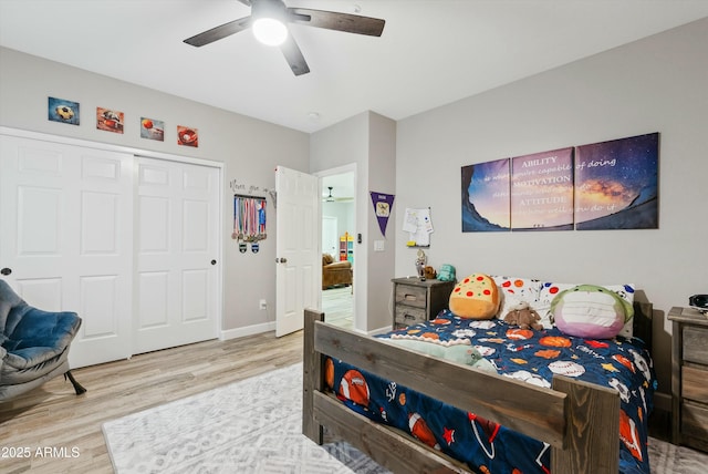 bedroom with a ceiling fan, a closet, light wood-style flooring, and baseboards